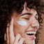 Image of model applying regenerative petal cream on their face