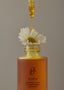 Close up image of the Renew product. There is a flower perched inside the bottle of the product. The dropper is dropping the serum onto the flower